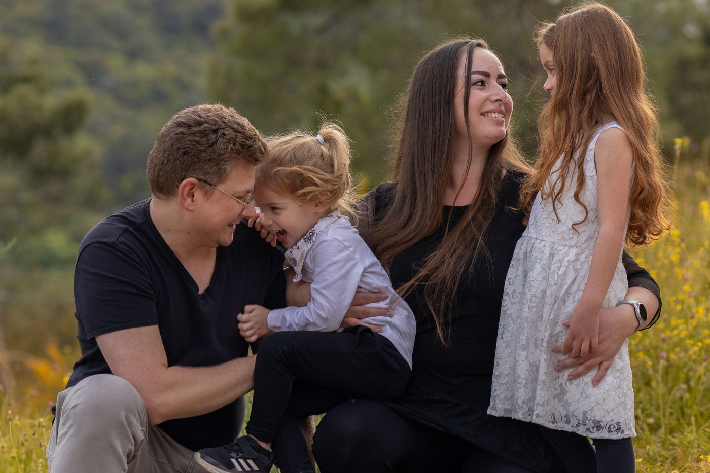 A family of four laughing together in a field