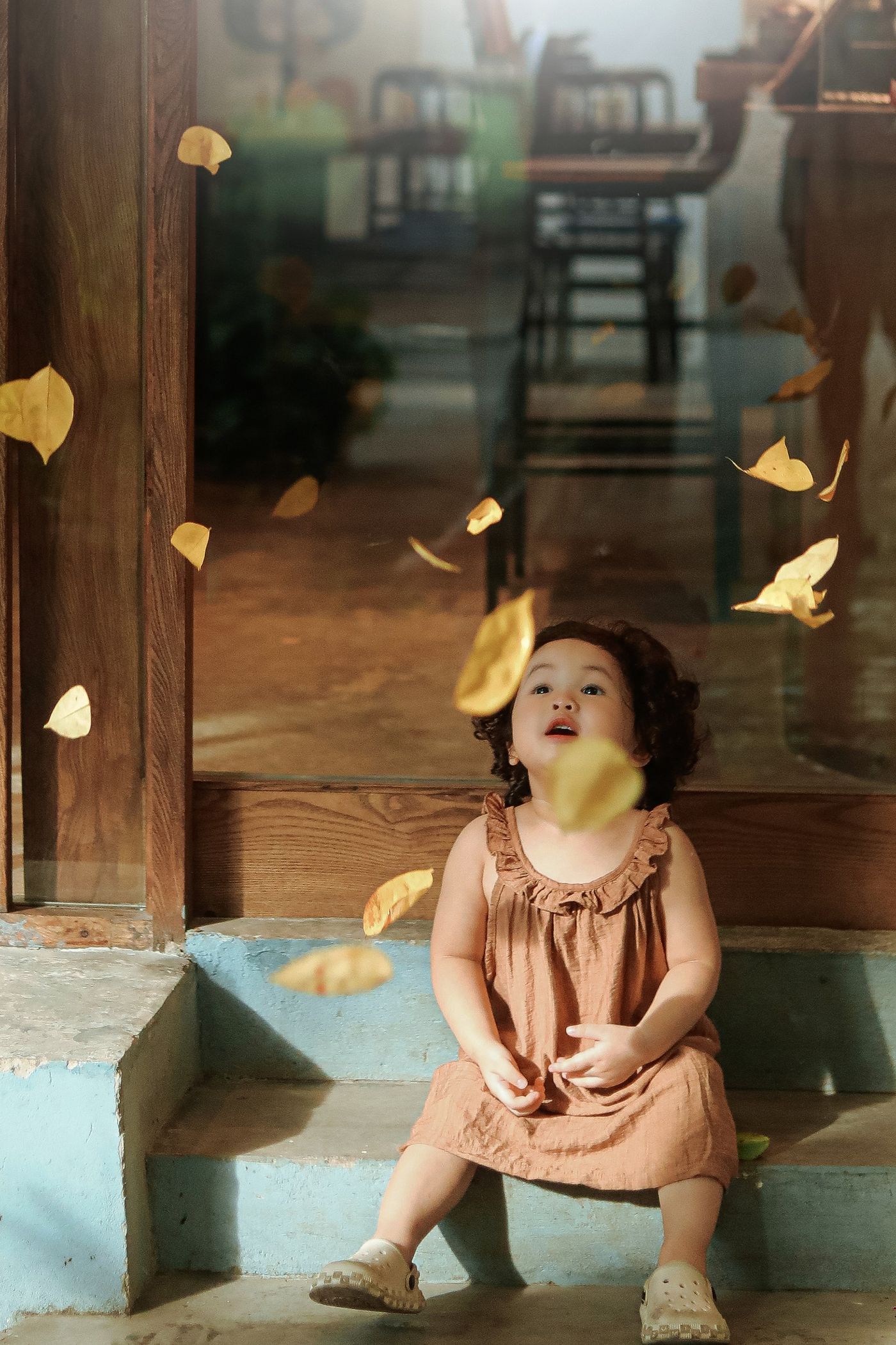 Little girl smiling as autumn leaves fall
