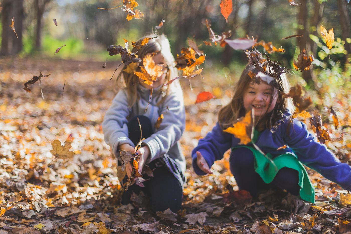 Two kids tossing autumn leaves