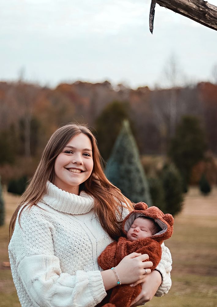 Mom holding her baby at a Christmas tree farm