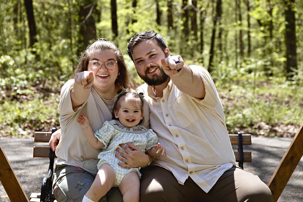 Family pointing and laughing on a park bench