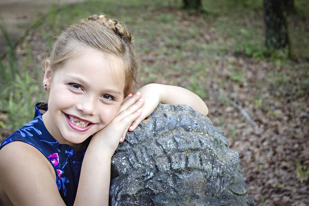 Little girl smiling on a stone turtle