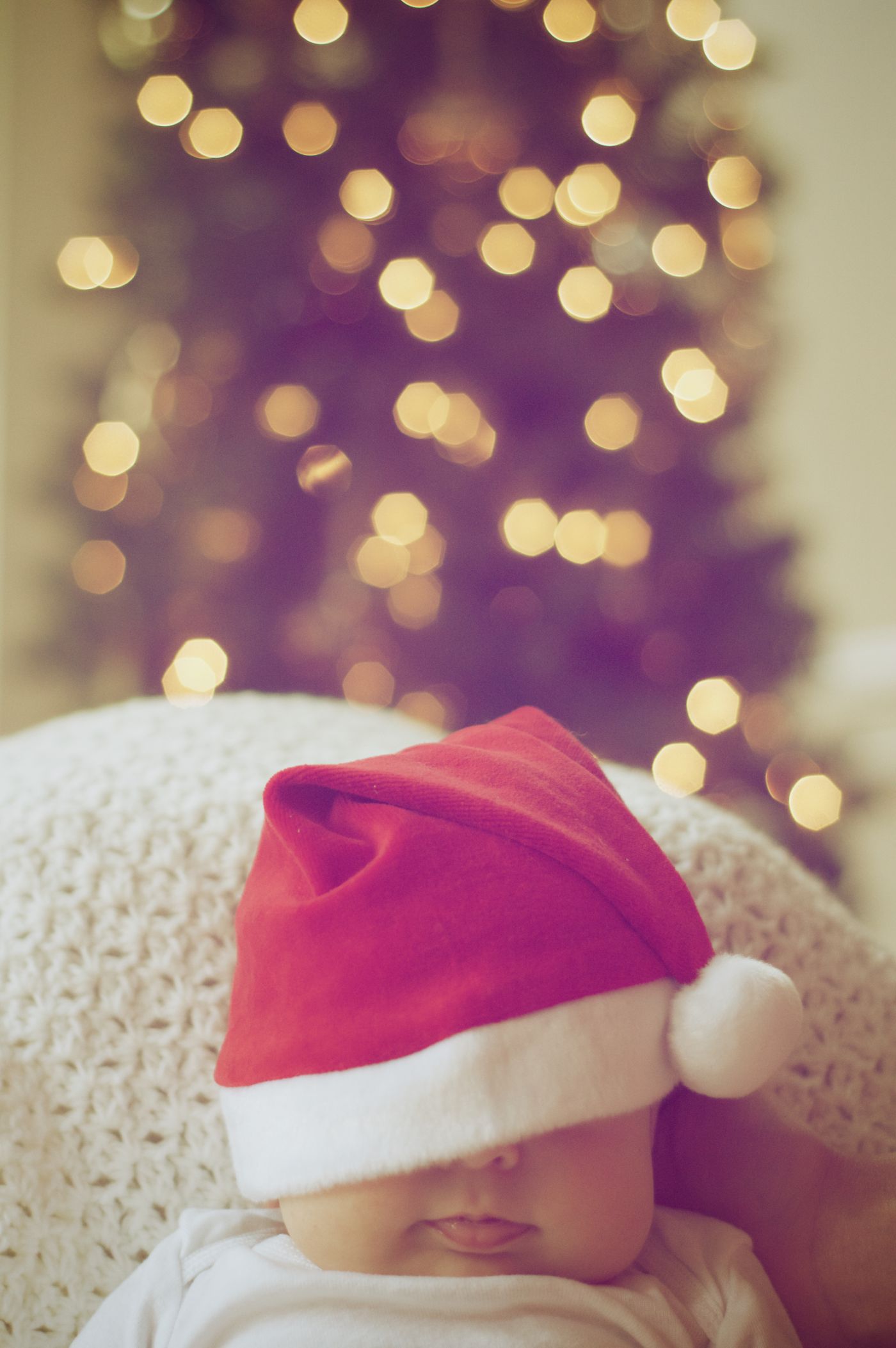 Baby in a Santa hat by the Christmas tree